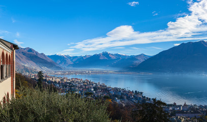 Stunning aerial panorama view of  Locarno cityscape and Lake Maggiore from Madonna del Sasso church, snow covered Swiss Alps mountain and blue sky cloud in background in autumn, Ticino, Switzerland