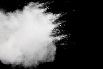 Freeze motion of white dust particles splash on black background.White powder explosion clouds.