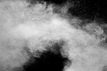 Freeze motion of white dust particles splash on black background.White powder explosion clouds.