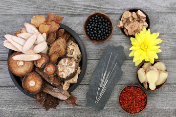 Traditional Chinese herbs, acupuncture needles and tablets to boost chi level used in herbal medicine on rustic wood background.