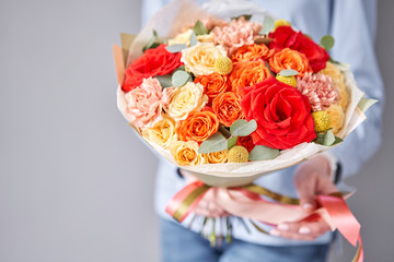 European floral shop. Beautiful bouquet of mixed flowers in woman hands. Work of the florist at a flower shop. Delivery fresh cut flower.