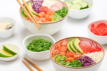 Hawaii salmon poke, avocado, rice, seaweed, cucumber, radish, carrot in bowl. Home made vegetarian poke. Seafood concept. Asian salmon poke salad on white background.
