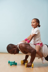 Father is doing push ups, using his little daughter as additional weight