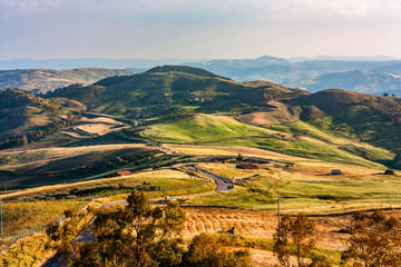 A landscape of colors of harvest time with fields, vineyards, groves and the road that snakes half towards the horizon and gets lost in the mountain.