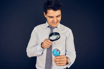 Young man examining world with magnifying glass