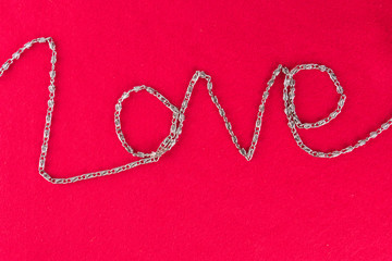 The inscription love lined with a silver chain on a pink velvet background.