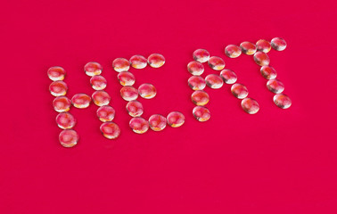 The inscription heat made of small transparent stones on a red background.
