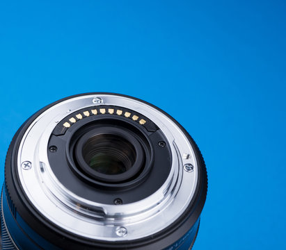 Part of the lens of the camera with bayonet mount, contacts aon a blue background.