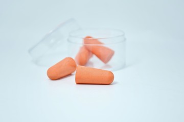 Orange earplugs in a clear box on a white background