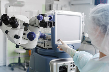 Mockup image, doctor working in operation room with special computer looking on display. Medical and technology concept