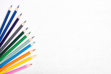 Flat lay composition with color pencils on light wooden background. Free copy space. Top view.