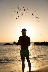 Hombre joven en la playa con gafas de sol y gorra disfrutando de la costa mediterránea de Cadiz,...