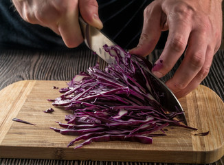 The man slices red cabbage.