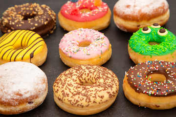 Dessert, Donuts, chocolate and strawberry circles, sugar and cream on Donuts and hot coffee cups, preparation for a break or party on the wooden table background.