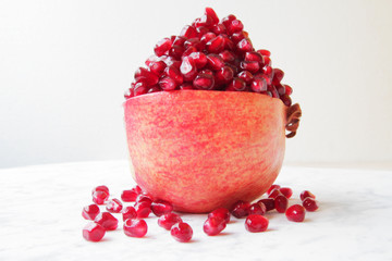  beautifully chopped pomegranate and its seeds, aesthetically laid out on a marble table.