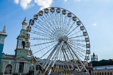 Ferris wheel in historical part of Kyiv. The bell tower of the former Greek monastery at the background. One of the most favorite squares among the locals. The Kontraktova Square. Kyiv, Ukraine
