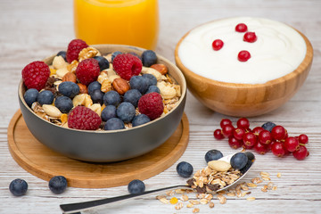 Bio Fruit Blueberry in bowl wood and Natural yogurt, kiwi, Raspberry, and nuts for health and diet with vitamin c in close-up on the wood table.