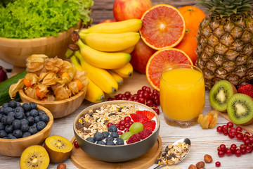Obraz na płótnie Canvas Group Fruits Breakfast mixed vegetables with salad bowl, nuts bowl, strawberry, banana, and pineapple, orange juice, vitamin c in food nature for health and diet in the top view on the wood table.