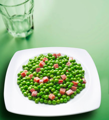 guisantes con jamón sobre fondo verde. peas with ham on a green background.