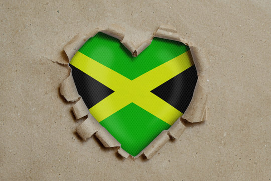 Heart shaped hole torn through paper, showing Jamaican flag