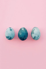 Natural dyed blue colored eggs on pastel pink background.