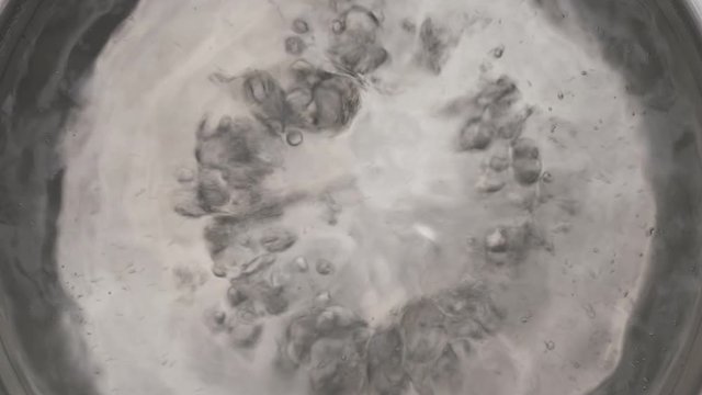 Top view of hot steaming water with bubbles boiling in metal pot. Isolated, on black background
