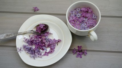cup and plate with lilacs on a wooden table. flowers lilac