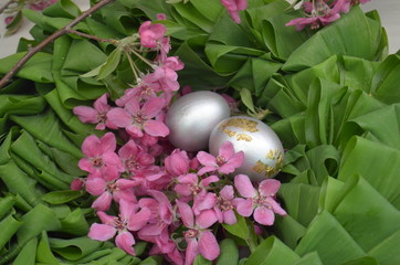 Beautiful festive wreath of green leaves with pink flowers and silver eggs. easter plants