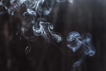 Image of backlit puffs of smoke, on a dark background.