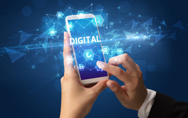 Female hand holding smartphone with DIGITAL inscription, modern technology concept