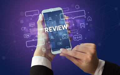 Female hand typing on smartphone with REVIEW inscription, social media concept