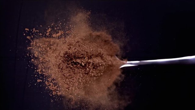 A Full Spoon Of exotic Christmas spice cinnamon anise and nutmeg falling down  on black background closeup in super slow motion