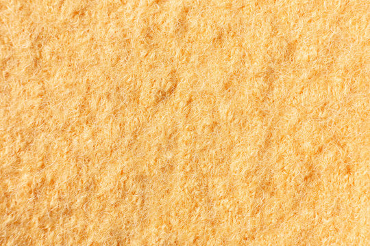 Light yellow background of felted wool, close up.
