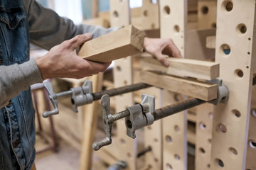 Man gluing furniture details in the carpentry workspace. Gluing furniture parts