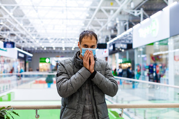 A young man in a medical mask in a shopping center. The masked man protects himself from the epidemic of the Chinese virus 