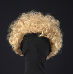 Curly blond hair wig on black background