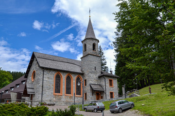 Fototapeta na wymiar chiesa di montagna con torre e cimitero