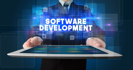 Fototapeta premium Young business person working on tablet and shows the inscription: SOFTWARE DEVELOPMENT