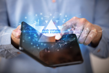 Businessman holding a foldable smartphone with OUR VISION inscription, business concept