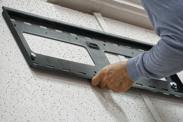 Hand holding install iron on the wall.