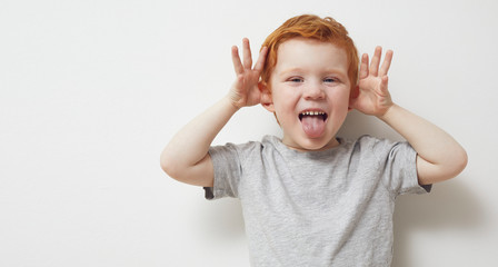 Redhead child and boy being silly and having fun in front of camera, showing silly face and...
