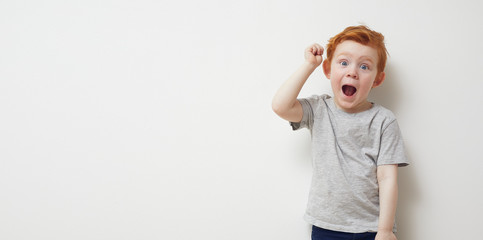 Over excited redhead boy cheering on a white background