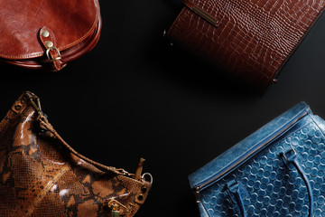 leather handbags of different colors on a black background top view, women's vintage leather handbags on black background, women's leather bags of different colors, women's handbags top view