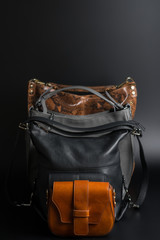 women's leather bags of different sizes one by one on a black background, leather bags of different types front view on black background, different types of leather women's handbags