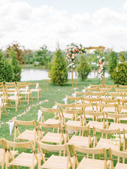 Beautiful romantic festive place made with wooden square and floral roses decorations for outside wedding ceremony in green park. Wedding settings at scenic place. 