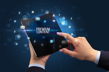 Businessman holding a foldable smartphone with PREMIUM CONTENT inscription, social networking concept