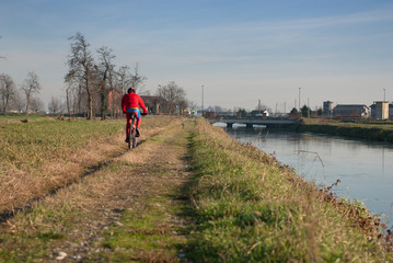 ciclista che pedala lungo il canale d'acqua