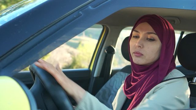 Muslim woman driving car. A modern Arab woman in a hijab parks her car in reverse