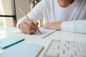 Close up hands with pen writing on notebook.