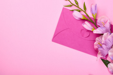 Envelope and flowers on pink background composition.
